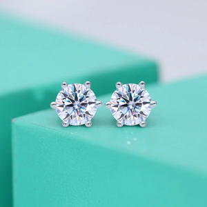 Macro shot of six-prong moissanite stud earring on light blue geometric display stand