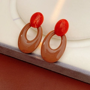 Detail of vintage hollow oval earrings featuring red beads and brown resin accents
