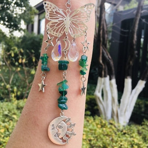 Detail of silver suncatcher with butterfly, green beads and moon charms on arm