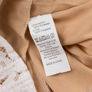 Detailed view of the garment wash care label with white lace fabric and 100% polyester info