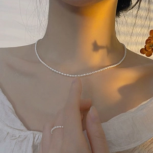Close-up of minimalist natural freshwater pearl necklace and matching ring on model