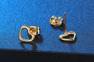 Macro detail of gold hollow heart stud earrings showing polished finish and secure backings