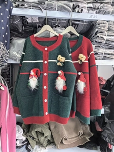 Detail view of festive red and green knitted doll cardigans with Santa and bear patches