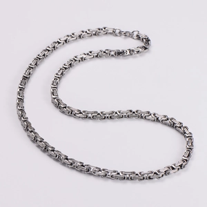 Macro view of silver stainless steel Byzantine chain with intricate square weave pattern
