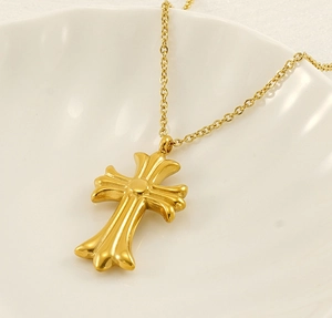 Macro shot of a gold cross pendant with diamonds on a white ceramic plate