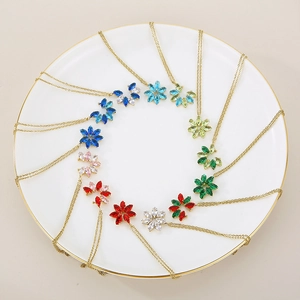 Gold-plated floral crystal necklace set in multiple colors on a ceramic tray