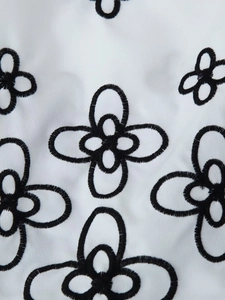 Detail of floral black embroidery on a white fabric shirt showing stitching texture
