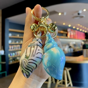 Colorful electroplated acrylic conch keychain with gold hardware held in hand