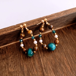 Detailed shot of vintage tiger eye and malachite beaded teardrop earrings on wood