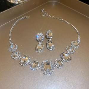 Macro detail of oval crystal necklace and earrings set with shimmering rhinestone pavé