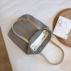 Vintage plaid canvas tote bag with beige leather handles on a white quilted background