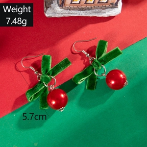 Gros plan de boucles d'oreilles nœud de Noël en velours vert avec perles rouges