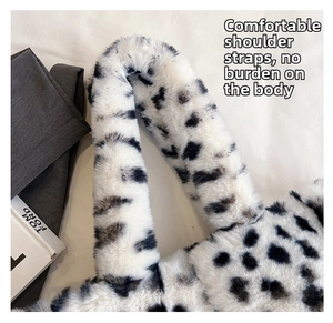 Dettaglio della tracolla larga in peluche della borsa con stampa mucca e texture soffice
