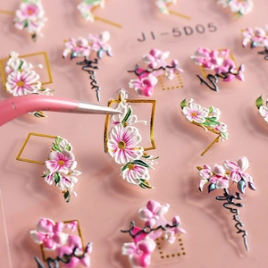 Close-up of tweezers picking up a 5D embossed pink flower nail sticker with gold border