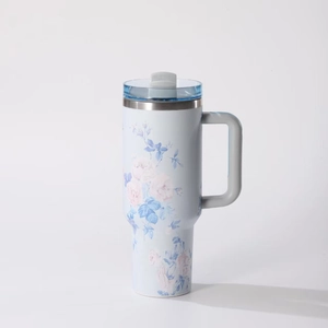 Dettaglio della tazza termica con manico e motivi di rose rosa e foglie blu su fondo blu