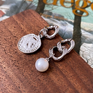 Detail of asymmetric silver earrings featuring a Swiss coin pendant and a white pearl drop