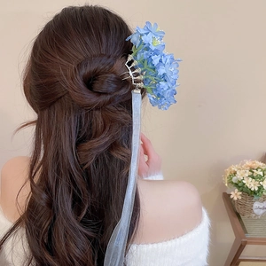 Detailed close-up of blue fabric flower hair pin with elegant white flowing ribbons