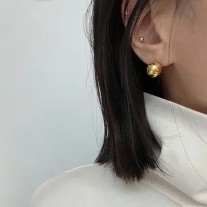 Close-up of polished gold spherical stud earrings in S925 sterling silver on model ear