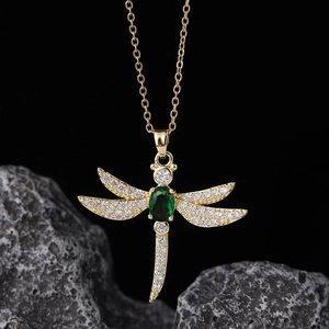 Detailed close-up of a gold-plated dragonfly necklace with green zircon on black stone