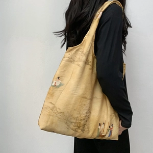 Detail of vintage Chinese landscape art on a large yellow canvas tote bag worn on shoulder