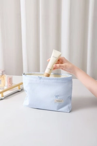 Détail d'une trousse de maquillage rayée bleu clair avec broderie papillon délicate