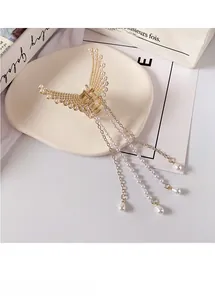 Detail of golden metal hair claw with wing design, white pearls and long hanging tassels