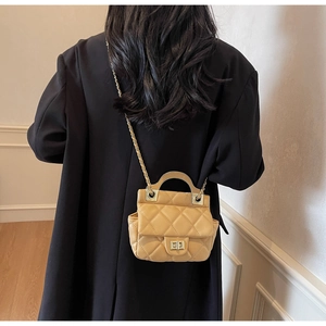 Model wearing yellow quilted crossbody bag with golden chain strap and top handle