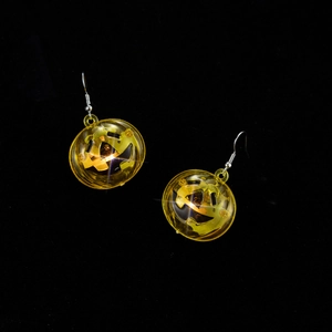Detailed view of glowing yellow Jack-o'-lantern earrings with silver hooks for Halloween