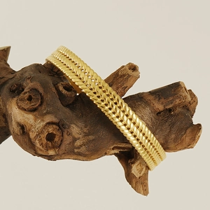 Détail d'un bracelet jonc doré à câble torsadé présenté sur une texture bois naturel