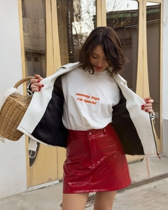 Detailed close-up of a glossy red patent leather mini skirt paired with a white jacket