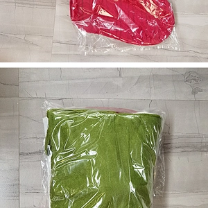 Close-up of red knitted Christmas hat and green towel in clear plastic packaging