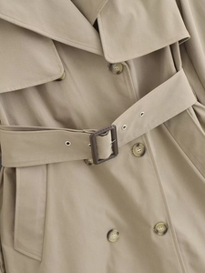 Detailed close-up of khaki trench coat featuring double-breasted buttons and matching belt