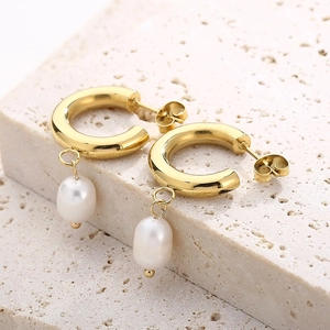 Vue macro de boucles d'oreilles dorées 18 carats avec perle sur pierre naturelle