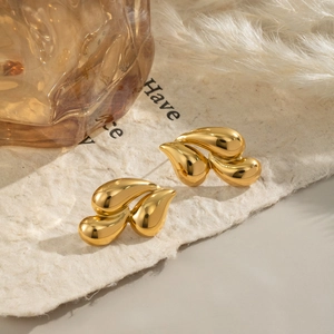Detail of 18K gold-plated stainless steel teardrop earrings on rustic paper background
