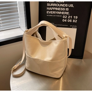 Close-up of cream bucket bag showing wrinkled leather texture and gold hardware details
