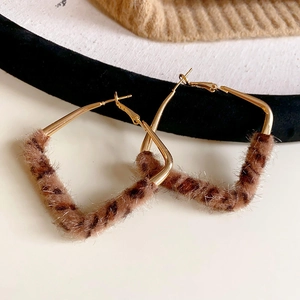Close-up of geometric trapezoid leopard print earrings with gold metal and velvet texture