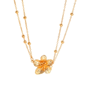 Gedetailleerde close-up van gouden frangipani bloem hanger en kralenketting textuur