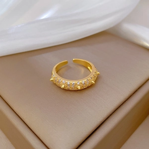 Gold open ring with micro-paved cubic zirconia and studs on silk background