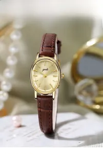 Detail of elegant gold oval watch dial and brown leather strap with retro accessories