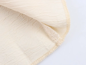 Dettaglio del tessuto in raso plissettato beige con cuciture pulite e trama stropicciata