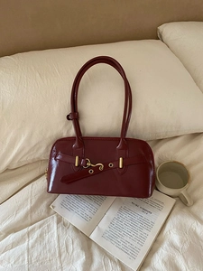 Retro deep red patent leather bowling handbag with gold hardware on white bedding