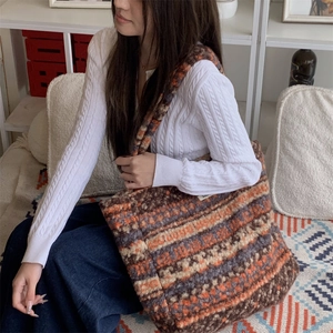 Detailed view of large ethnic plush tote bag with geometric pattern worn by a model