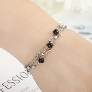 Three-layer stainless steel bead bracelet with brown beads on a woman's wrist