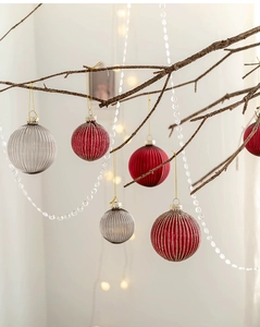 Detail of red and grey striped glass Christmas balls hanging on tree with warm bokeh lights