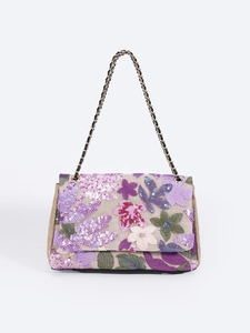 Detail of floral embroidery and sequins on a woven shoulder bag with gold chain