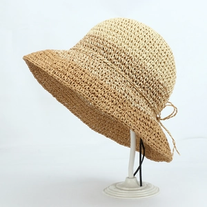 Detailed close-up of handmade crochet straw hat featuring a bicolor weave and bow detail