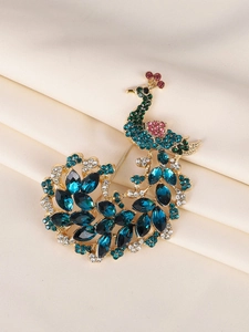 Close-up of golden peacock brooch with vibrant blue crystals on beige silk fabric