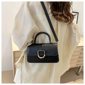Close-up of minimalist black PU leather crossbody bag with metal buckle and shoulder strap