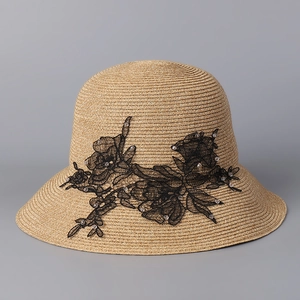 Detail of straw hat with black lace floral embroidery and delicate white pearls