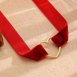 Dettaglio del girocollo in velluto rosso con fibbia centrale in metallo a cuore oro